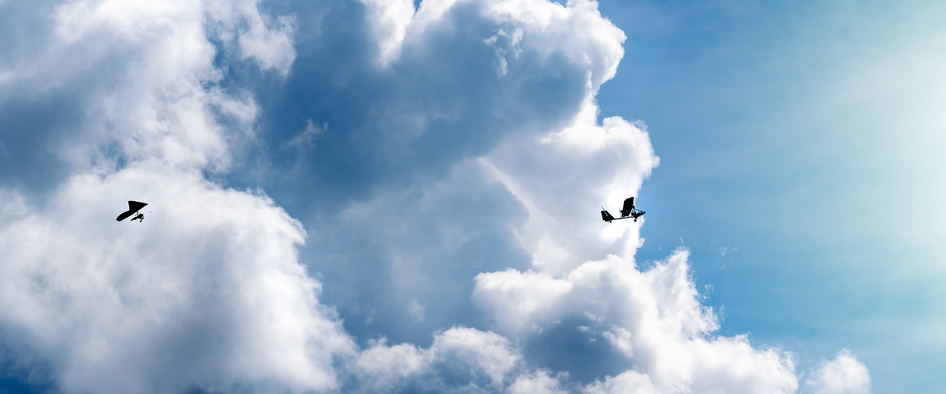 Hang glider and tug towing by large clouds