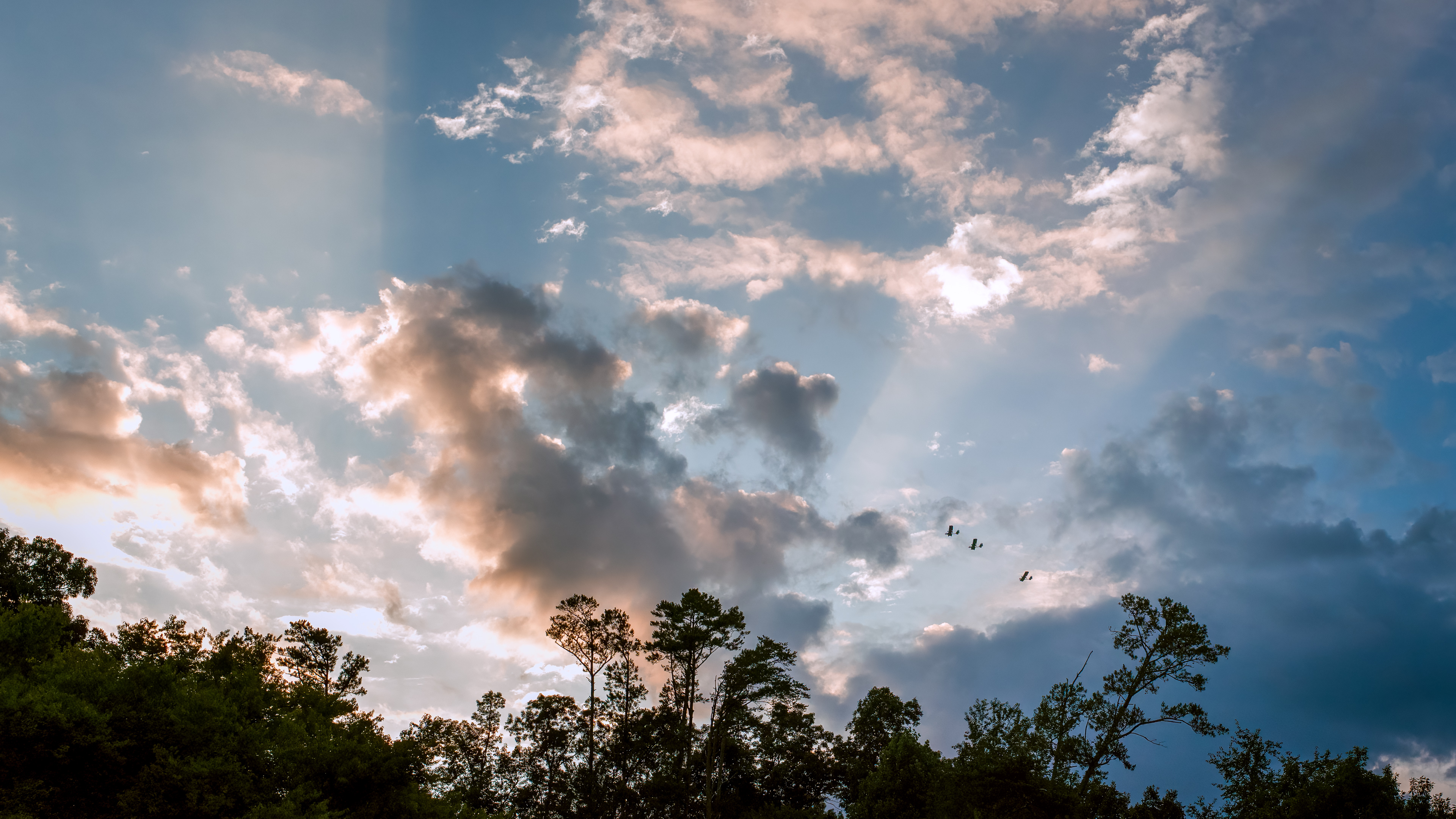 Tug pilots flying over the valley between rays from a sunset