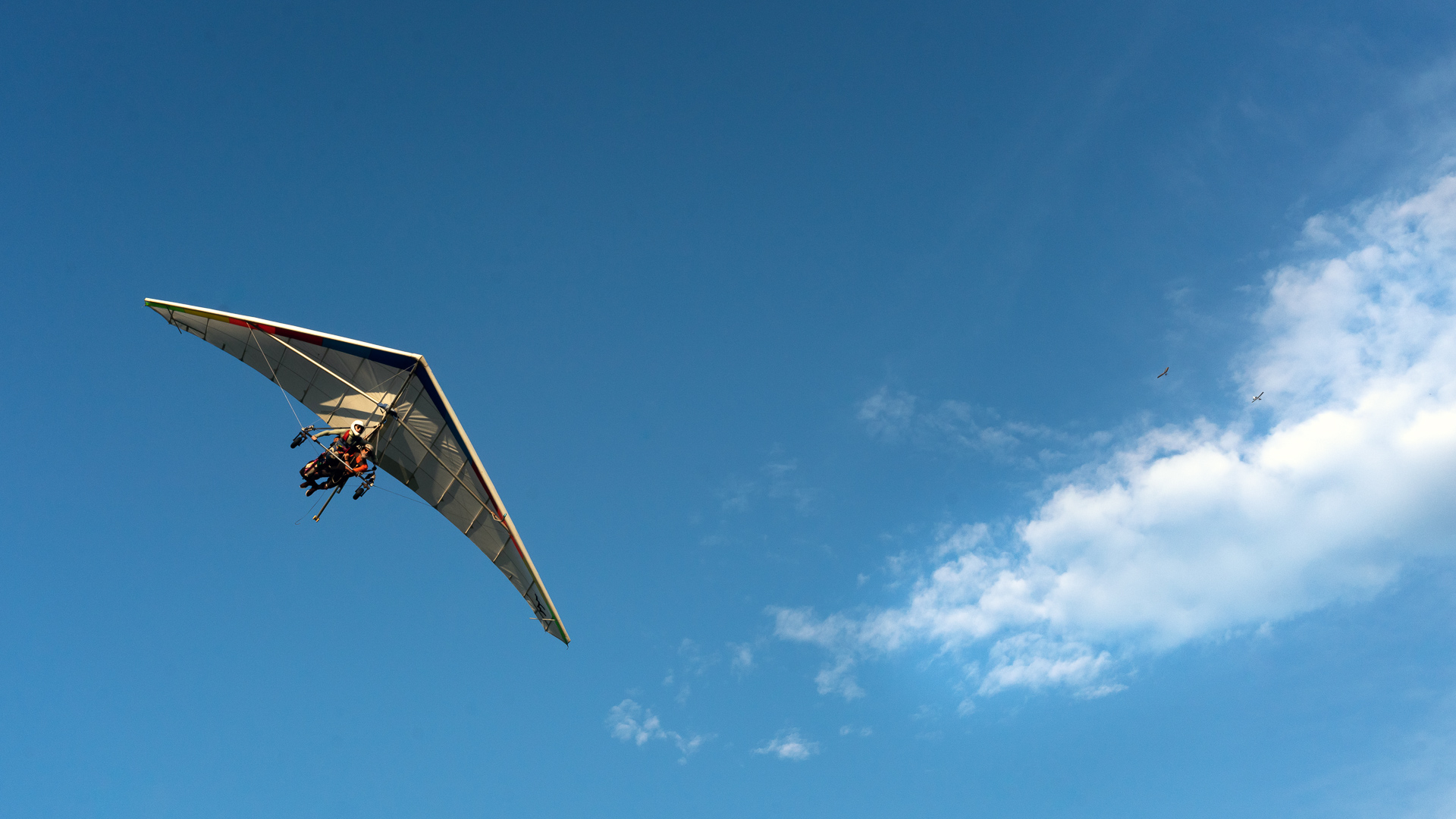 Tandem hang glider landing with tow plane in the background